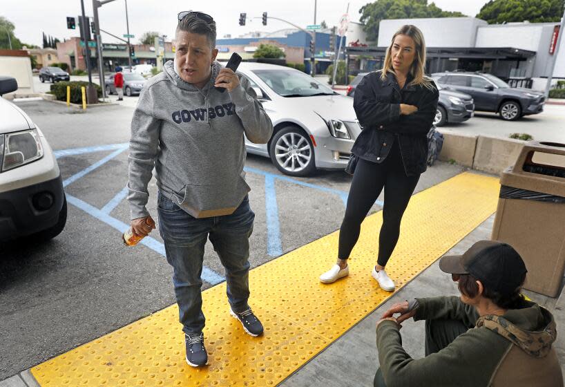 PASADENA-CA-MAY 11, 2023: Crisis interventionist Vicki Lucas, left, is accompanied by Emily Spencer, center, who works for Lucas on a freelance basis-part of a larger network of assistants that Lucas maintains for intervention work throughout the state and the country, as they provide Sherry Hill's daughter, right, with a chance to speak on a phone with Hill outside of a 7-Eleven convenience store in Pasadena on May 11, 2023. (Christina House / Los Angeles Times)