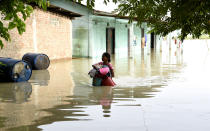 A woman carries her household belongings to a safer place in a flood-affected village of Kamrup district of Assam, India, on July 14, 2020. Villages in Assam were flooded due to heavy rains. The rising water level inundated houses, residents were forced to move to a safer place. (Photo by Hafiz Ahmed/Anadolu Agency via Getty Images)