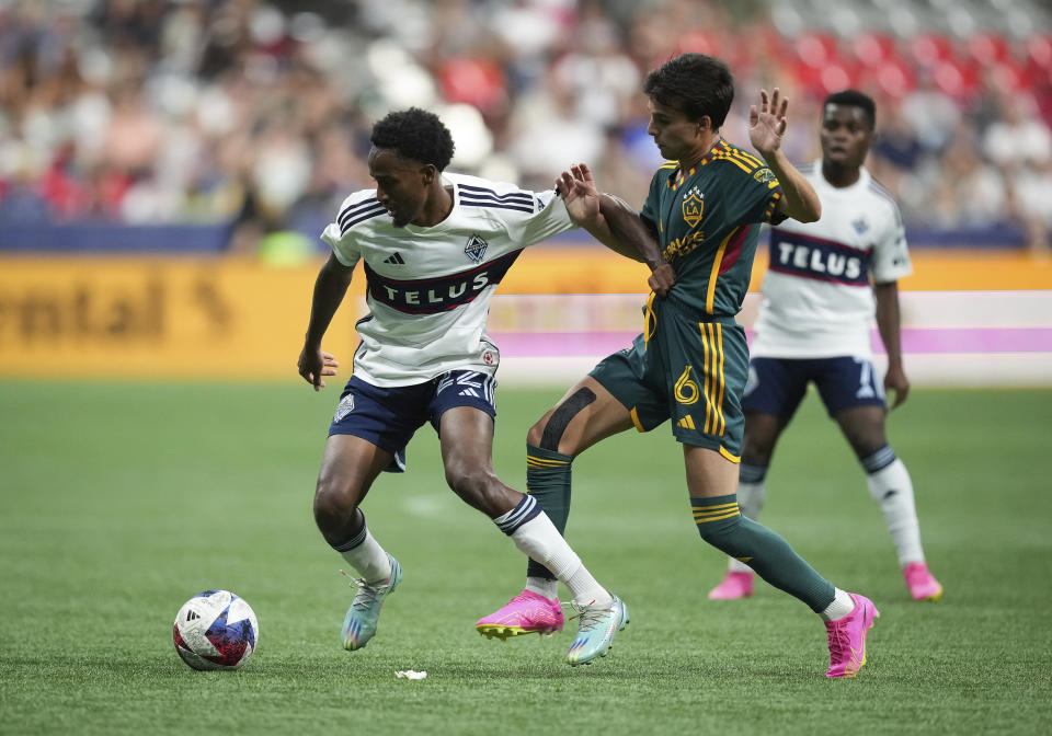 Vancouver Whitecaps' Ali Ahmed, left, and Los Angeles Galaxy's Riqui Puig vie for the ball during the second half of an MLS soccer match Saturday, July 15, 2023, in Vancouver, British Columbia. (Darryl Dyck/The Canadian Press via AP)