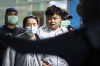 Parit Chiwarak is escorted after being arrested at the police station in Bangkok