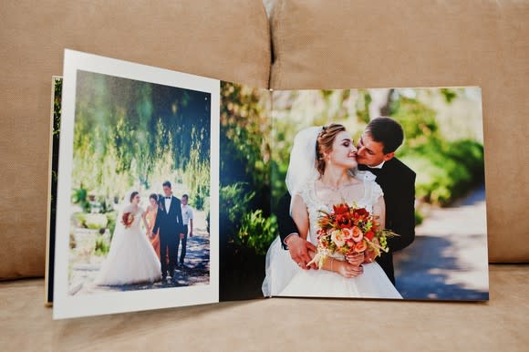 A wedding photo book open showing two pictures of the bride and groom.