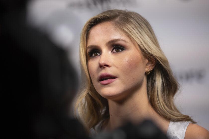 A side-profile picture of a young blond woman with gold hoop earrings. A dark figure obstructs the bottom left of the image