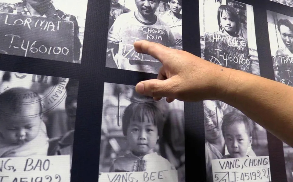 Car Yang, Project Director for Vinai, the Hmong Refugee Experience, shows a few of the 800 photographs displaying temporary alien numbers for immigration approval during a tour of the exhibit Friday, Dec. 23, 2022 in Fresno.