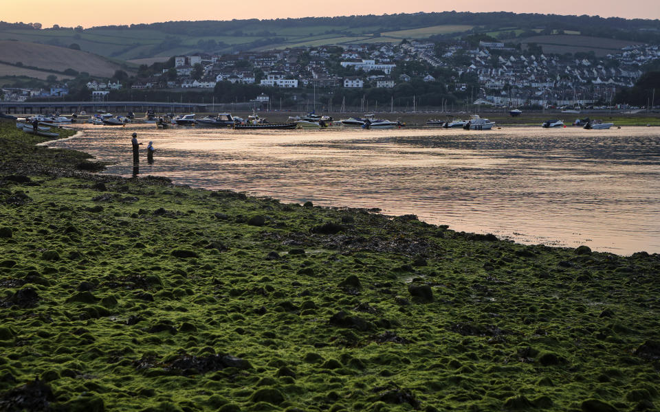 People fish in the Teign estuary in Shaldon, Devon, England as the sun sets on Tuesday July 20, 2021. (AP Photo/Tony Hicks)