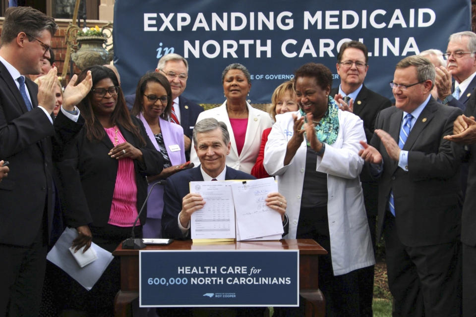 North Carolina Democratic Gov. Roy Cooper signs a Medicaid expansion law at the Executive Mansion on Monday, March 27, 2023, in Raleigh, N.C. Advocates say the bill could help 600,000 adults. (AP Photo/Hannah Schoenbaum)