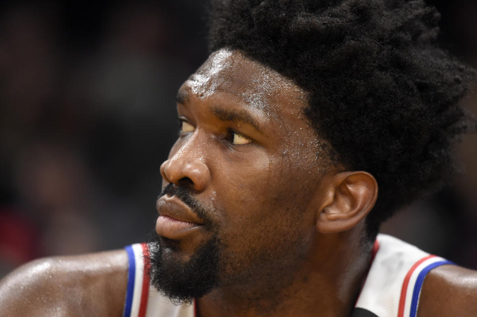 Joel Embiid watches from 76ers bench.