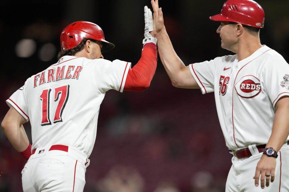 Cincinnati Reds' Kyle Farmer (17) high-fives third base coach J.R. House after hitting a solo home run during the sixth inning of the team's baseball game against the Milwaukee Brewers on Thursday, Sept. 22, 2022, in Cincinnati. (AP Photo/Jeff Dean)