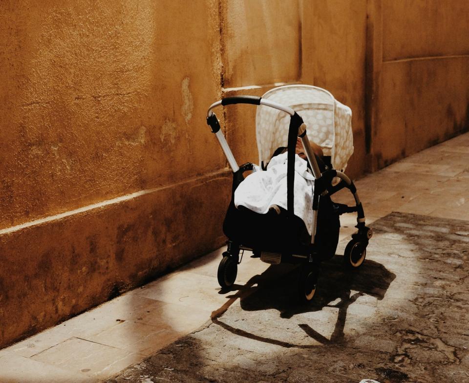 A baby in a stroller in an alley