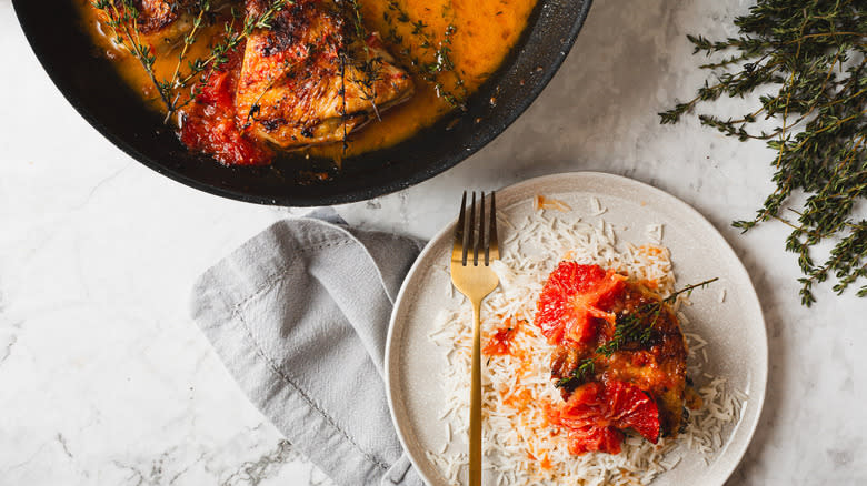 Chicken in plate over rice with large pan in the back