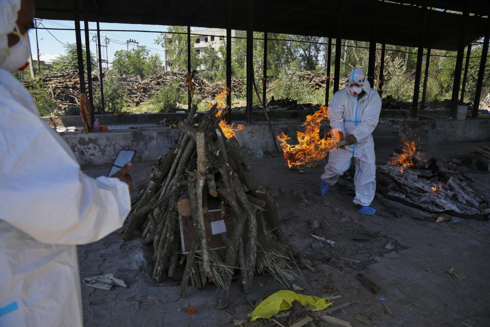 A family member lights the funeral pyre of a COVID-19 victim during cremation in Jammu, India, Monday, May 24, 2021. India crossed another grim milestone Monday of more than 300,000 people lost to the coronavirus as a devastating surge of infections appeared to be easing in big cities but was swamping the poorer countryside. (AP Photo/Channi Anand)