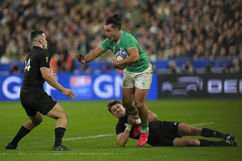 Ireland's James Lowe is tackled by New Zealand's Beauden Barrett and New Zealand's Will Jordan, left, during the Rugby World Cup quarterfinal match between Ireland and New Zealand at the Stade de France in Saint-Denis, near Paris Saturday, Oct. 14, 2023. (AP Photo/Thibault Camus)