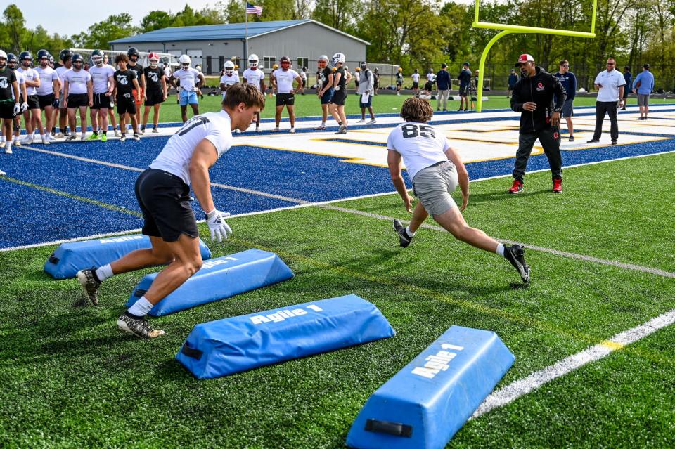 Sexton football coach Johnel Davis, right, runs a drill with athletes during a MHSAA/MHSFCA spring football evaluation camp on Tuesday, May 16, 2023, at DeWitt High School.