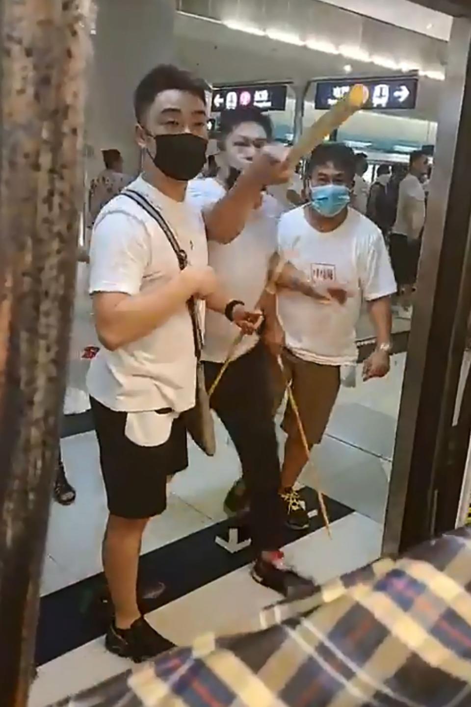 A mob of men in white T-shirts threaten pro-democracy protesters during clashes at Yuen Long station (AFP/Getty Images)