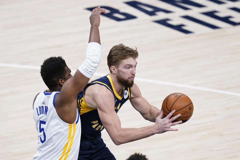 Indiana Pacers' Domantas Sabonis, right, passes the ball as Golden State Warriors' Kevon Looney (5) defends during the first half of an NBA basketball game Wednesday, Feb. 24, 2021, in Indianapolis. (AP Photo/Darron Cummings)