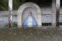 A statue of the Virgin Mary is seen partially submerged in flood water as it rains in Sorrento, Louisiana. REUTERS/Jonathan Bachman