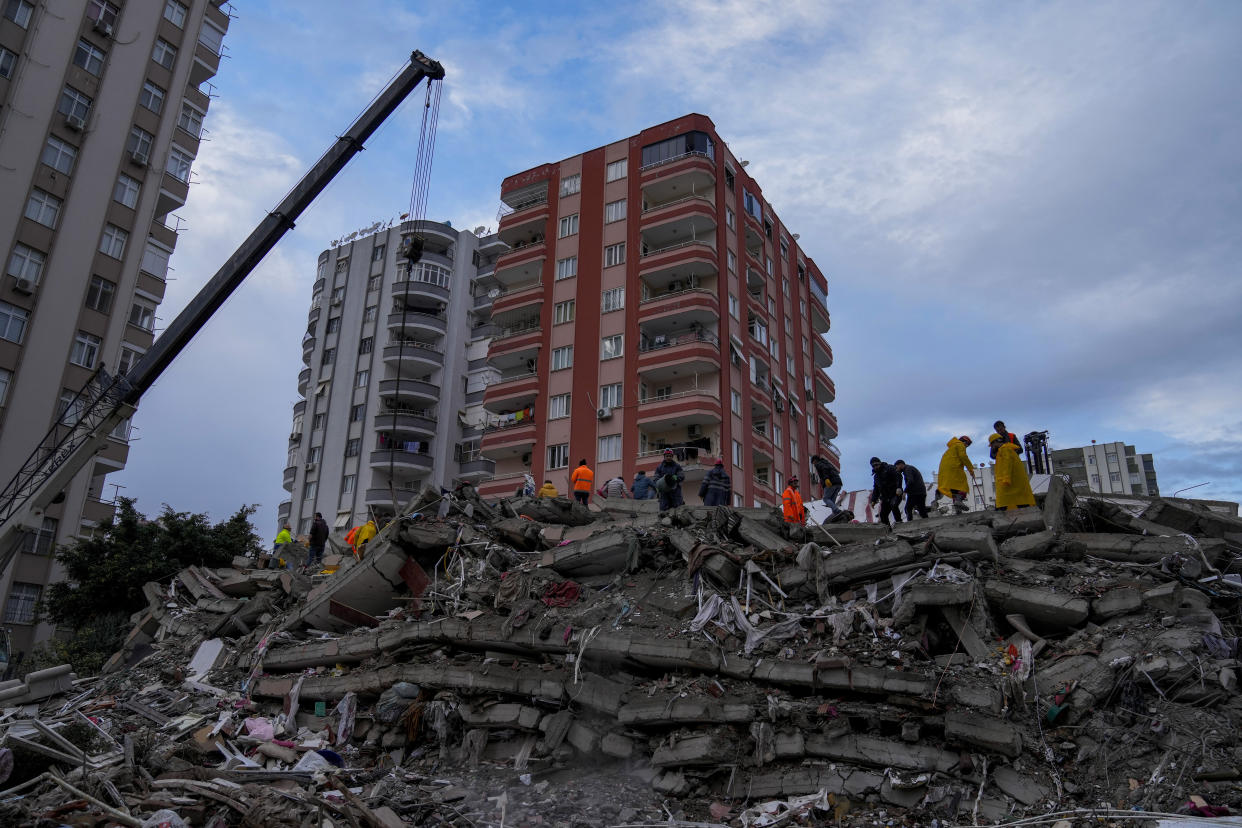 People and emergency teams search for people in a destroyed building in Adana, Turkey, Monday, Feb. 6, 2023. A powerful quake has knocked down multiple buildings in southeast Turkey and Syria and many casualties are feared. (AP Photo/Khalil Hamra)