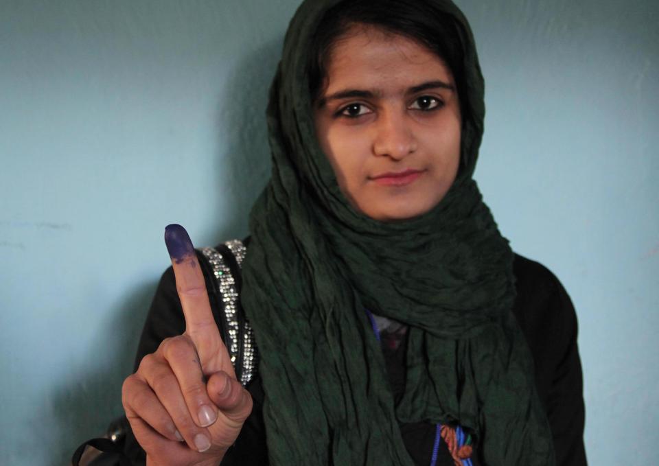 An Afghan young woman shows her inked finger after casting her vote at a polling station in Herat, Afghanistan, Saturday, April 5, 2014. (AP Photo/Hoshang Hashimi)