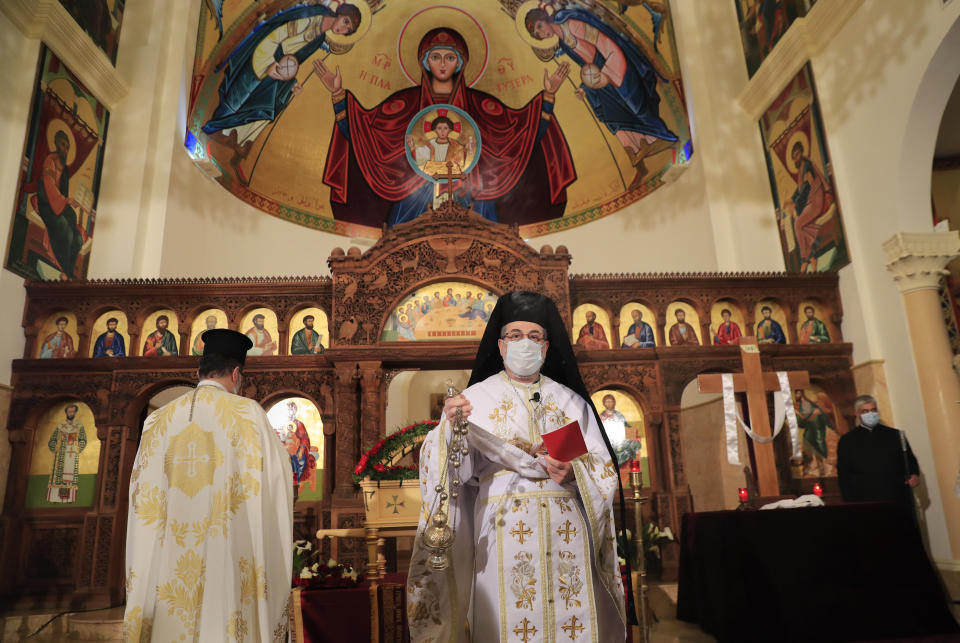 A priest wears a mask to protect from COVID-19, as he performs rituals during a Good Friday Mass for the Passion of Christ, at a church in Beirut, Lebanon, Friday, April 2, 2021. Christians in Lebanon observed Good Friday under a COVID-19 lockdown and amid a severe economic crisis exacerbated by the massive explosion that demolished parts of the capital last year. Even traditional Easter sweets are a luxury few can afford. (AP Photo/Hussein Malla)