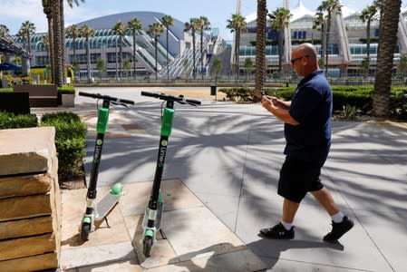 Dan Borelli of Scoot Scoop logs in two scooters left on private property with an app on his phone before impounding the devices in San Diego , California