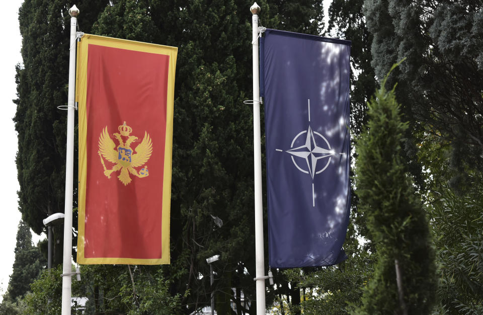 In this photo taken Monday, Nov. 11, 2019, the Montenegro, left, and NATO flags wave in front of the Montenegrin Defense Ministry in Podgorica, Montenegro.Deployed inside the sprawling communist-era army command headquarters in Montenegro’s capital, a group of elite U.S. military cyber experts are plotting strategy in a fight against potential Russian and other cyberattacks ahead of the 2020 American and Montenegrin elections. (AP Photo/Risto Bozovic)