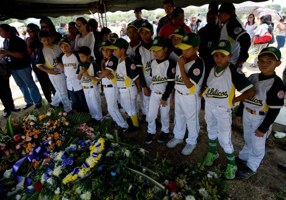 In this photo taken on Friday, March 14, 2014. Boys that play in a minor league baseball team "Atleticos de Crimon" mourn their coach, Guillermo Sanchez after his funeral grave in in Valencia, Venezuela. The people of the poor district of La Isabelica were made to pay for taking to the streets in anti-government protests. More than a dozen masked men on motorcycles roared through, shooting up a barricade and killing a university student and a 42-year-old man painting his house. (AP Photo/Fernando Llano)