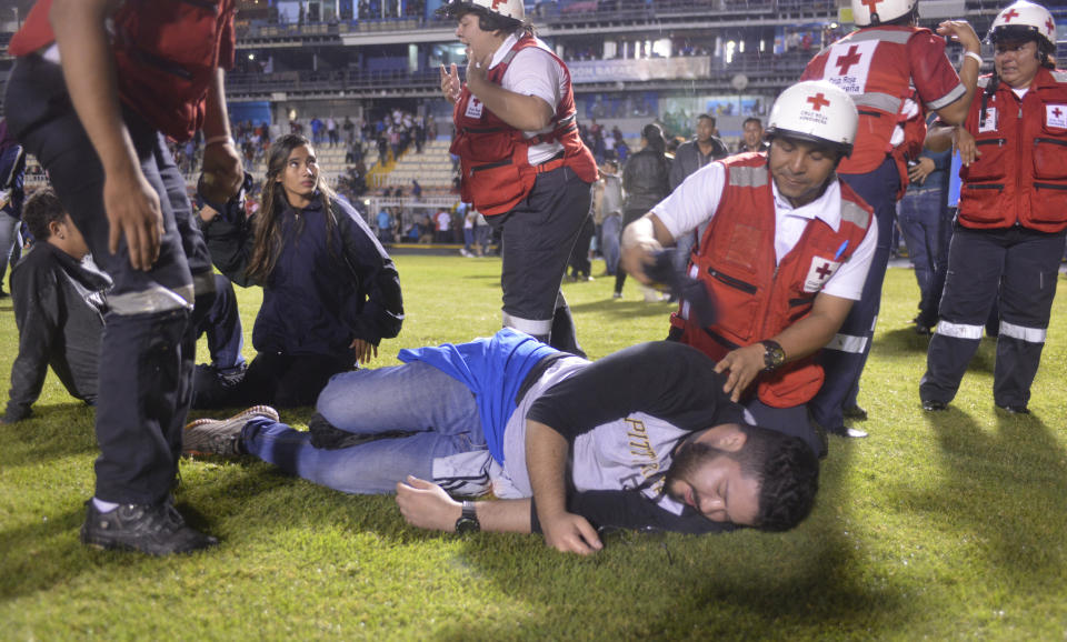 Soccer fans affected by tear gas fired by police are helped by members of the Red Cross after a deadly fight broke out between fans before the start of a game between Motagua and Olimpia, inside the national stadium in Tegucigalpa, Honduras, late Saturday, Aug. 17, 2019. The fight between fans of rival soccer teams outside the stadium left three people dead and led to the suspension of the game. (Victor Colindres/La Tribunal via AP)