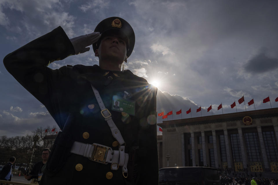 A Chinese paramilitary policeman salutes as delegates leave in buses from the Great Hall of the People after the closing session of the National People's Congress in Beijing, Monday, March 11, 2024. (AP Photo/Ng Han Guan)
