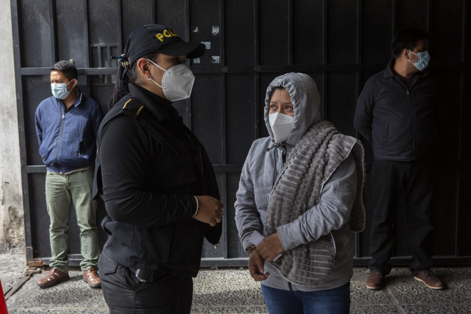 La detenida Ana Mateo Baltasar aparece esposada junto a un oficial de policía después de que ella y los también arrestados Abel Mateo, detrás a la izquierda, y Andrés Francisco Fernando, detrás a la derecha, fueran escoltados a la corte después de una operación policial contra presuntos traficantes de migrantes en la Ciudad de Guatemala, el martes 2 de agosto de 2022. (Foto AP/Oliver de Ros)