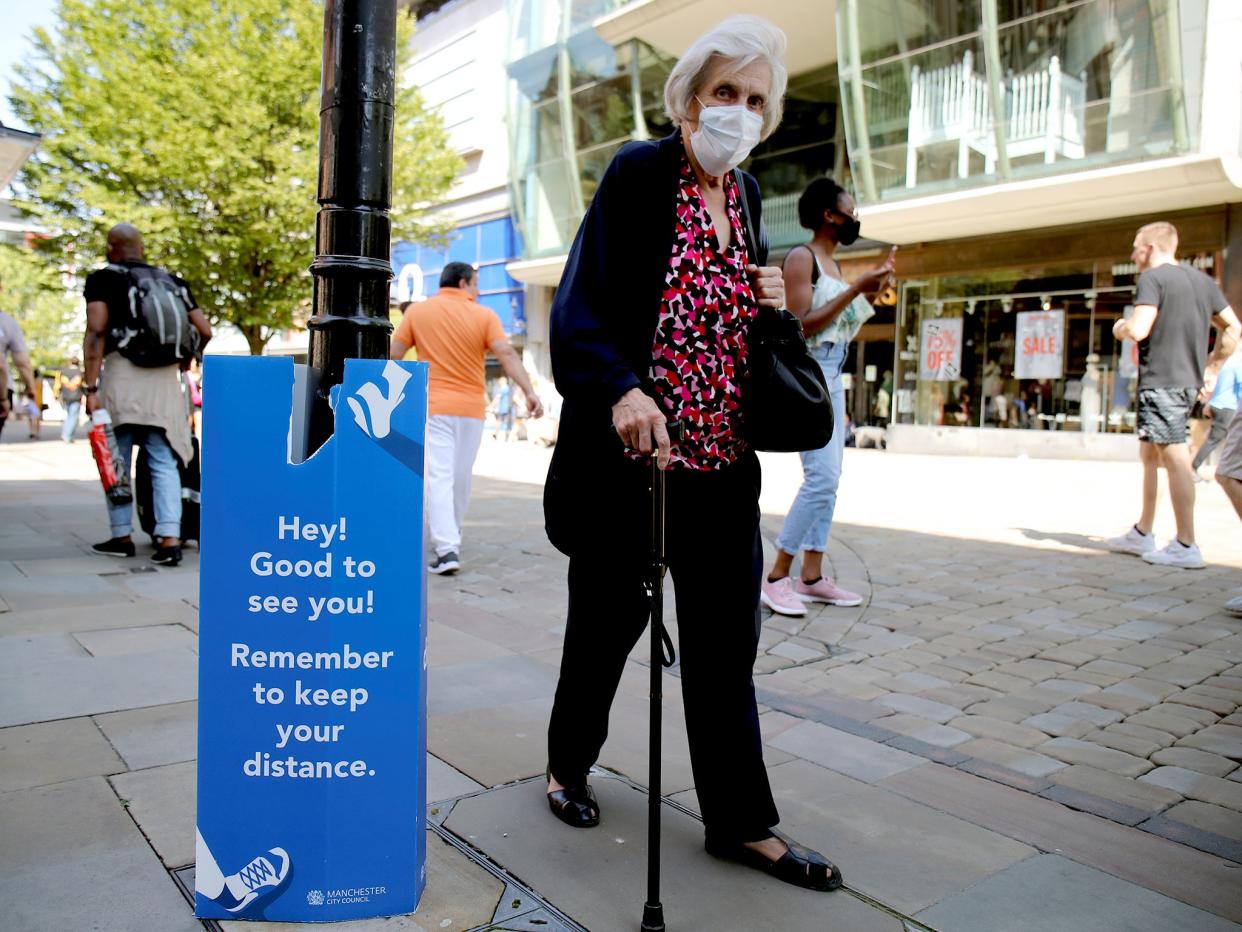 A woman wearing a protective mask walks down the street in Manchester as the city and surrounding areas face local restrictions amid a coronavirus outbreak: Reuters