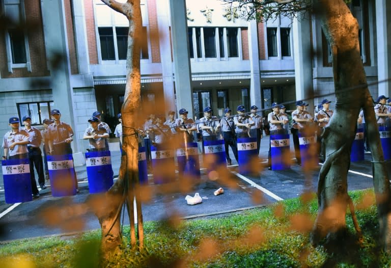 Local policemen stand guard outside the Education Ministry in Taipei during a demonstration of student protesters on July 30, 2015