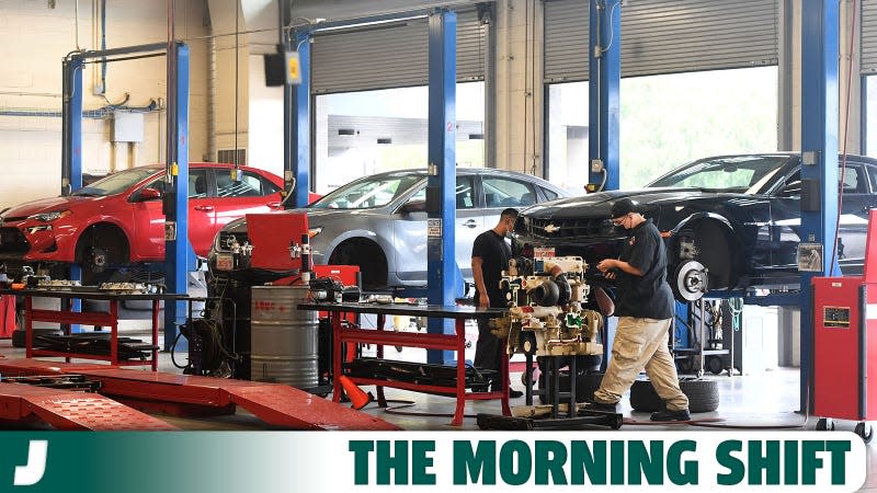 A photo of three cars waiting for repairs in a shop. 