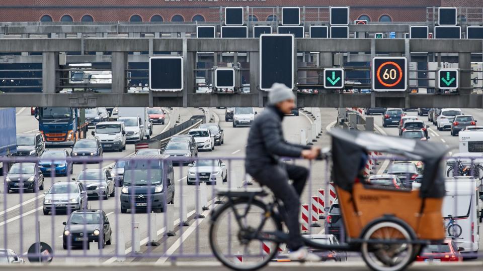 Ein Lastenrad-Fahrer fährt in Hamburg über die A7, auf der sich vor dem Elbtunnel der Verkehr staut.