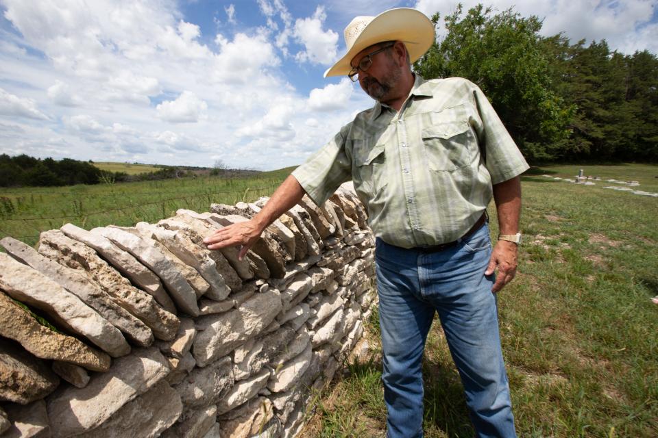 Chuck Kidd explains why the top dressing of limestones are positioned the way they are on a native stone fence in the Alma City Cemetary last Thursday. Kidd is among those who help with yearly workshops to restore the fences in the area.