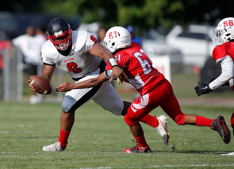 Sexton quarterback Dequarius Jones scrambles against pressure from Everett's Antonio Williams, Friday, Aug. 26, 2022, in Lansing.