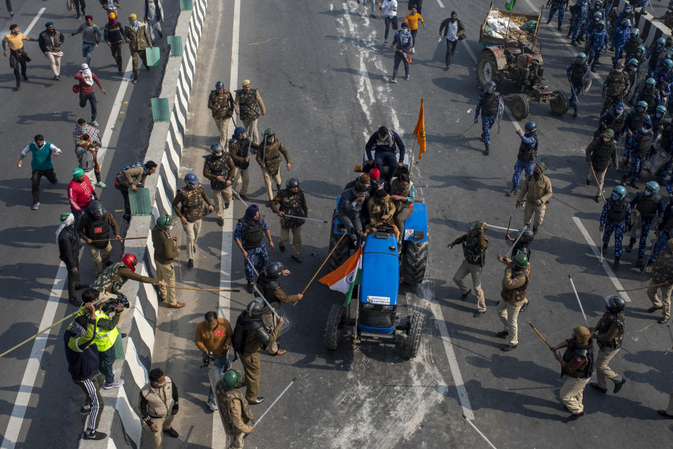 FILE - In this Tuesday, Jan.26, 2021, file photo, Indian policemen beat farmers driving a tractor towards the heart of the city as a sign of protest against new farm laws, during India's Republic Day celebrations in New Delhi, India. Following the farmer protests, the mainstream and social media have come under unprecedented attacks from Prime Minister Narendra Modi’s Bharatiya Janata Party. The trigger for the clampdown was the death of a protester, Navneet Singh, when the largely peaceful rallies turned violent on Jan. 26 after a group of farmers veered from an agreed protest route and stormed New Delhi’s 17th century Red Fort. Farmer leaders condemned the violence but refused to call off the protest. Authorities say no shots were fired and that Singh died because his tractor overturned. His family alleged he was fatally shot. (AP Photo/Altaf Qadri, File)