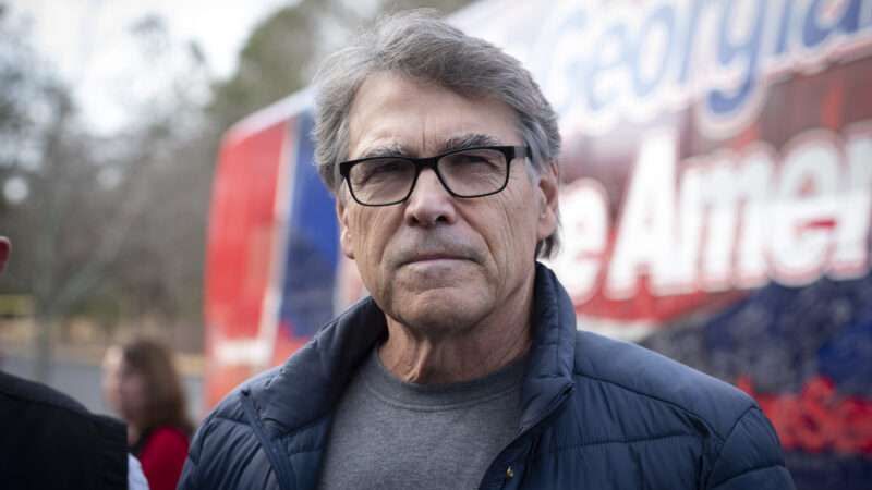 Rick Perry standing in front of a campaign bus