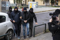 Plain-clothed policemen escort handcuffed well-known actor and director Dimitris Lignadis to a magistrate's office in Athens, Sunday, Feb. 21, 2021. Lignadis, 56, the former artistic director of Greece's National Theatre, has been arrested on rape charges, police say. (AP Photo/Yorgos Karahalis)