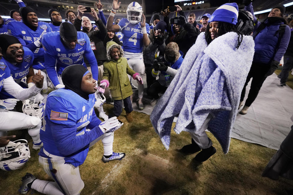 Air Force running back John Lee Eldridge III, kneeling left, proposes to his girlfriend, Shanice Atkins, right, after Air Force's 30-15 win over Baylor in the Armed Forces Bowl NCAA college football game in Fort Worth, Texas, Thursday, Dec. 22, 2022. Atkins said yes. (AP Photo/LM Otero)