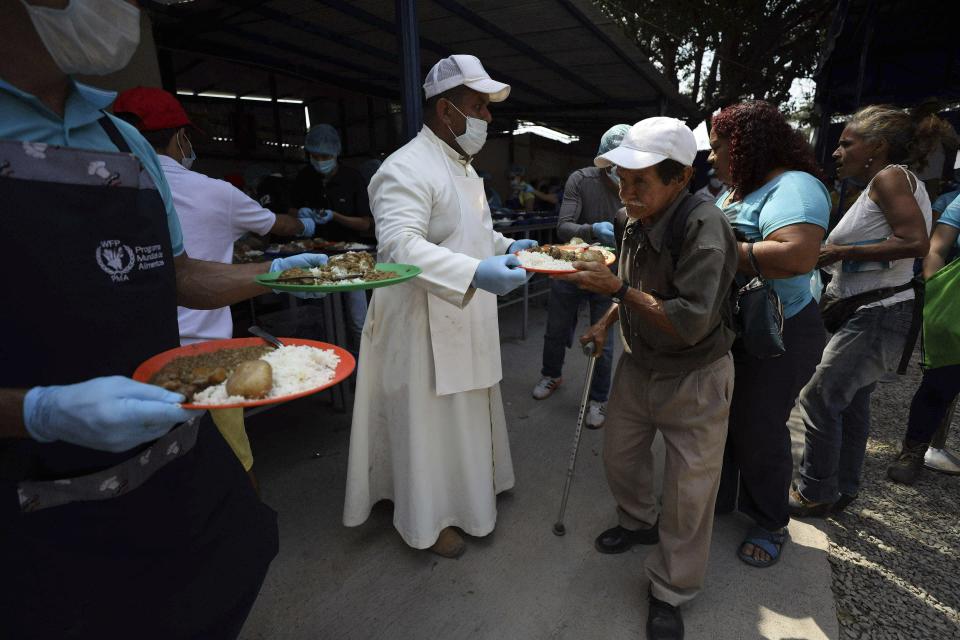 FILE - In this Monday, Feb. 11, 2019 file photo, priest Richard Garcia hands out free lunch to Venezuelan migrants at the "Divina Providencia" migrant shelter in La Parada, near Cucuta, on the border with Venezuela, Colombia. On Friday, Feb. 15, 2018, The Associated Press has found that stories circulating on the internet that the food is contaminated, are untrue. (AP Photo/Fernando Vergara)