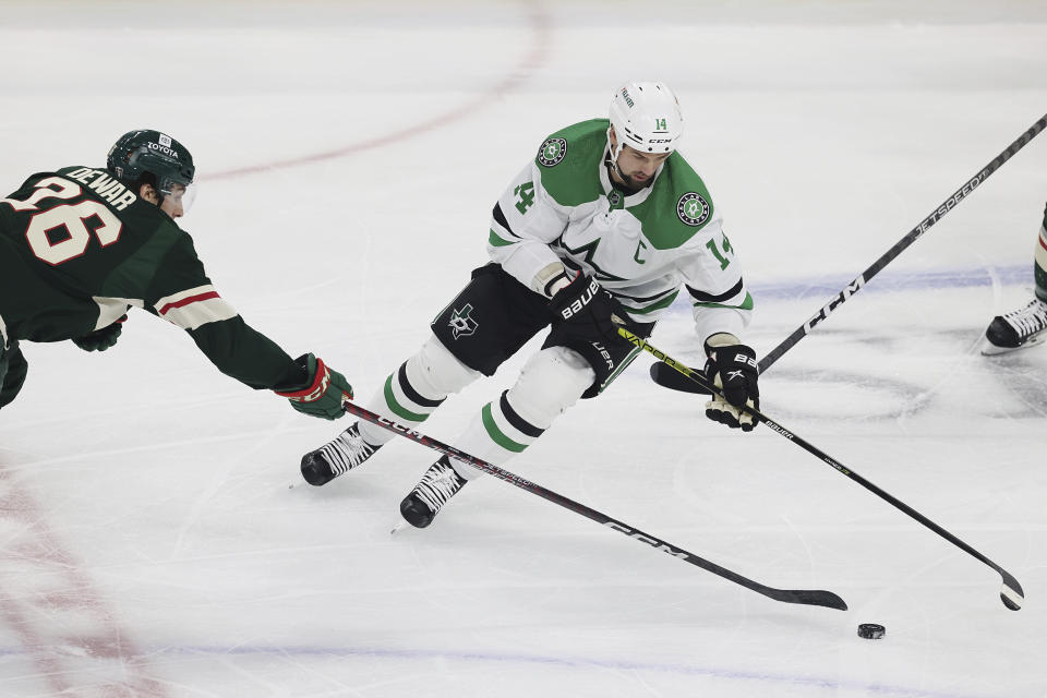 Dallas Stars left wing Jamie Benn (14) handles the puck next to Minnesota Wild center Connor Dewar (26) during the first period of Game 3 of an NHL hockey Stanley Cup first-round playoff series Friday, April 21, 2023, in St. Paul, Minn. (AP Photo/Stacy Bengs)