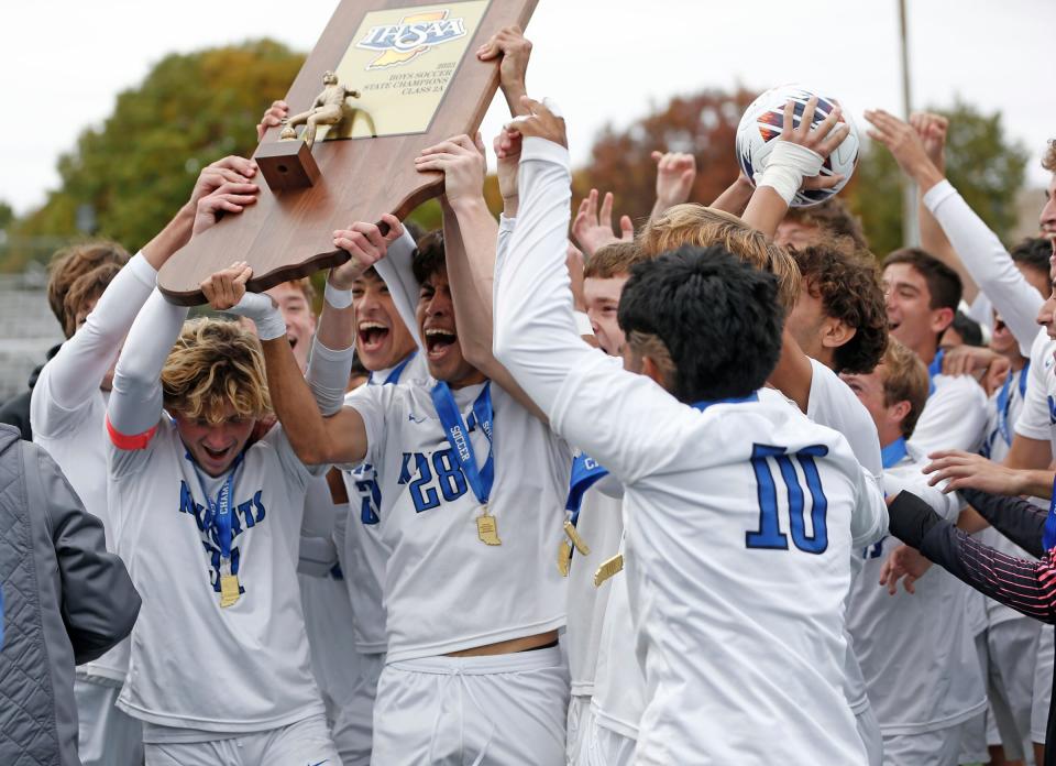 The Mishawaka Marian boys soccer team raises the state championship trophy after beating Evansville Memorial, 4-0, in the IHSAA Class 2A title game Saturday, Oct. 28, 2023, at Carroll Stadium in Indianapolis.