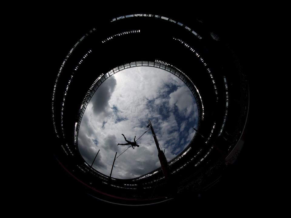 An upward view shows a pole vaulter with the sky in the background at the Olympics