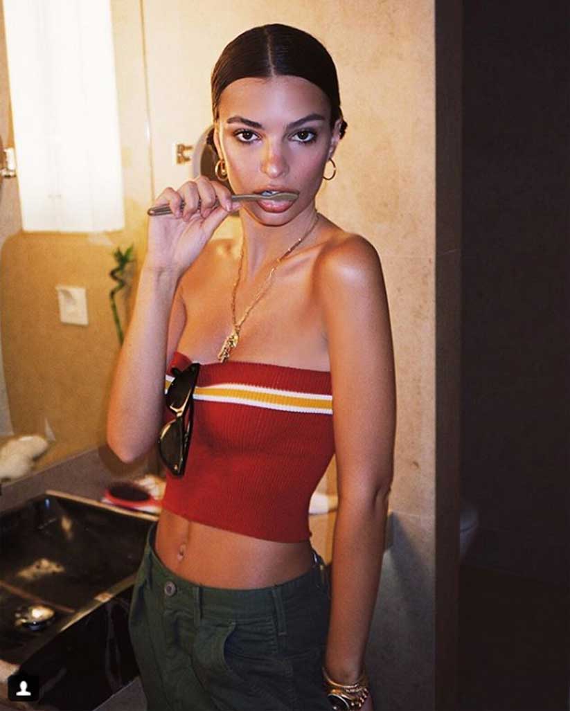 Emily Ratajkowski wears a red, white, and yellow crop top by Donni with gold hoops and jewelry.