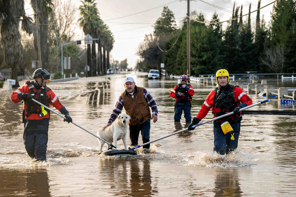 Image: San Diego firefighters help Humberto Maciel rescue his dog  from his flooded home in Merced, Calif., on Jan. 10, 2023. (Josh Edelson / AFP - Getty Images)