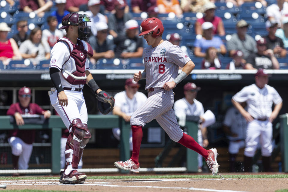 Oklahoma outfielder John Spikerman (8) scores a run against Texas A&M in the first inning during an NCAA College World Series baseball game Friday, June 17, 2022, in Omaha, Neb. (AP Photo/John Peterson)