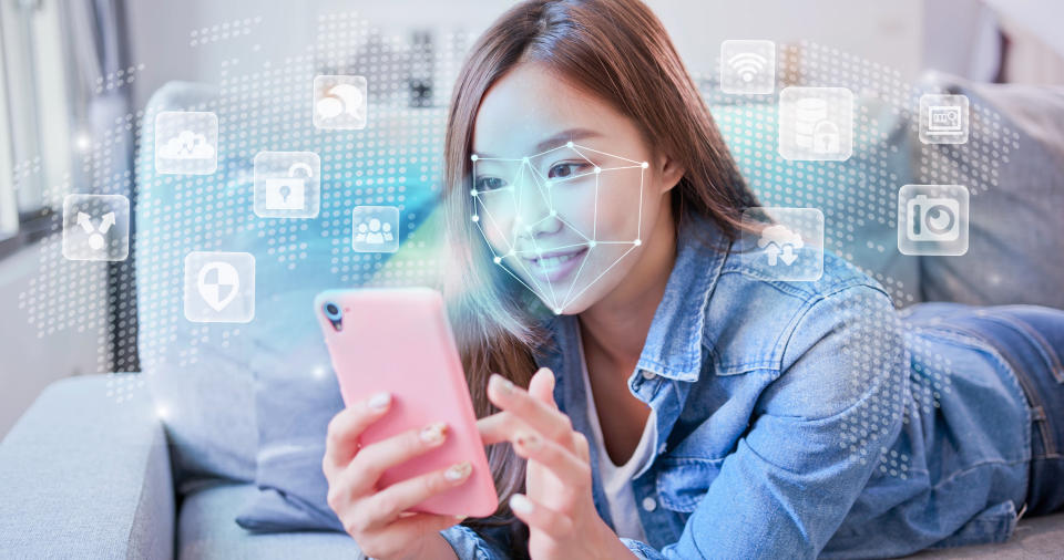 A young woman on a couch while using her mobile phone.