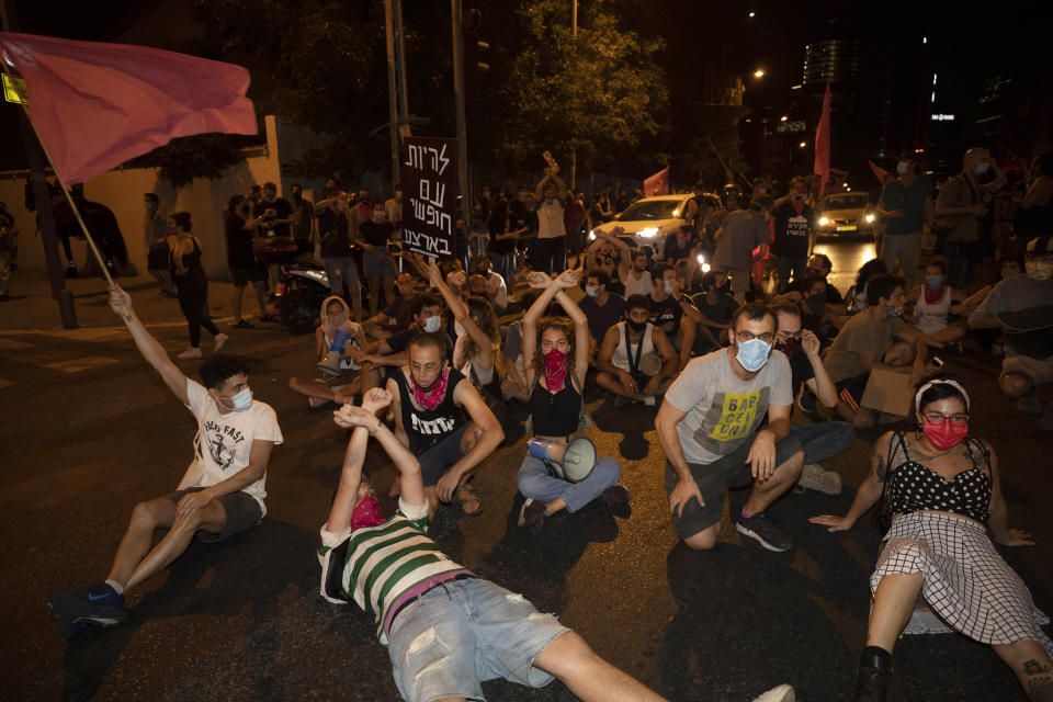 Israeli protesters sit on the street during a demonstration against lockdown measures that they believe are aimed at curbing protests against Prime Minister Benjamin Netanyahu, in Tel Aviv, Israel, Thursday, Oct. 1, 2020. (AP Photo/Sebastian Scheiner)