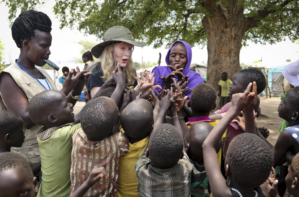 In this photo taken Tuesday, April 2, 2019, human rights activist Mia Farrow, center-left, plays a game with children during a visit to an internally displaced person's camp in the capital Juba, South Sudan. Human rights activist Mia Farrow spoke to The Associated Press as she visited South Sudan again in her new role as envoy for the International Rescue Committee, helping the aid group to promote a global initiative to change the way humanitarian organizations approach malnutrition. (AP Photo/Sam Mednick)