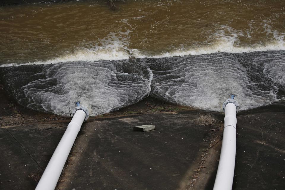 Lake water flows from the additional drainage pumps on the Oktibbeha County Lake dam near Starkville, Miss., Wednesday afternoon, Jan. 15, 2020. Officials are hoping the additional drainage will limit the heavy pressure the rain-swollen lake is placing on the dam. County officials believe a breach would affect an estimated 130 properties and several highways. (AP Photo/Rogelio V. Solis)