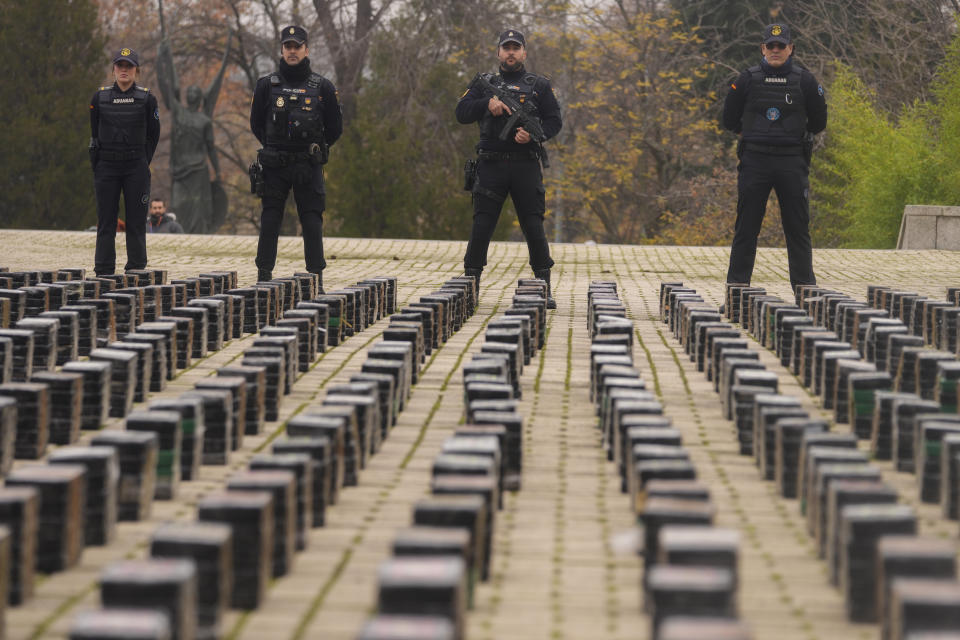 Police officers stand by part of a haul of 11 tons of cocaine, displayed in the patio of a police station in Madrid, Spain, Tuesday, Dec. 12, 2023. Spanish authorities say that they have confiscated 11 tons of cocaine and arrested 20 people in two different operations against the smuggling of the illegal drugs inside shipping containers. Investigators believe that the criminal organization was using a frozen seafood company as a front to bring the drug from South America. (AP Photo/Paul White)